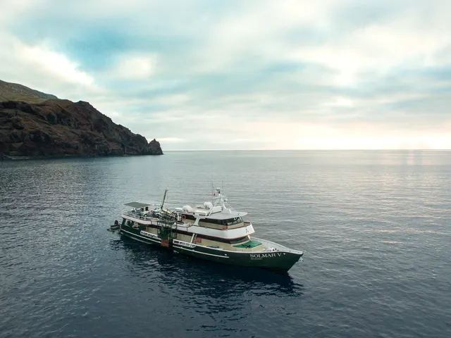 Liveaboard da immersione all'alba davanti a un'isola vulcanica in mare aperto