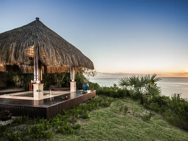Gazebo spa con jacuzzi e tetto in paglia al tramonto con vista sul mare
