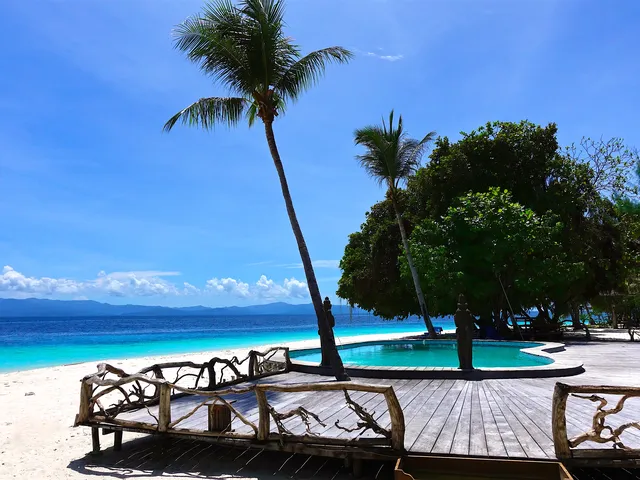 Terrazza in legno di un resort tra le palme affacciata su una spiaggia dal mare turchese